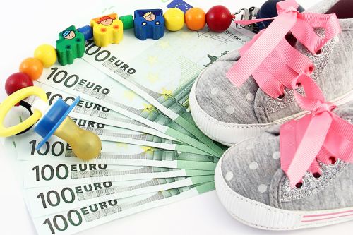 Schnuller und Kinderschuhe auf Geldscheinen